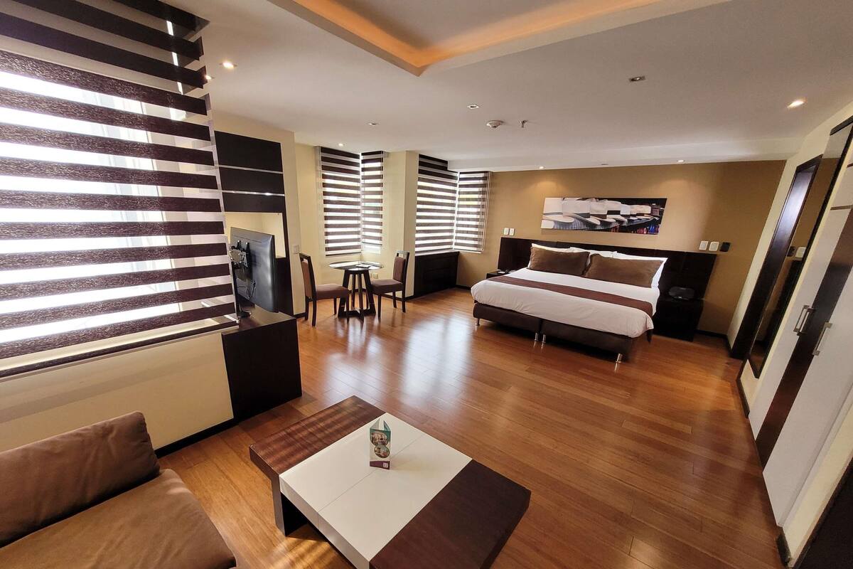 A modern hotel room with a bed, a desk, a chair, and a TV.