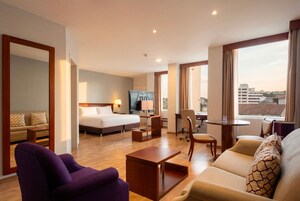 Una habitación de hotel con cama, escritorio, sillón, sofá y televisión.