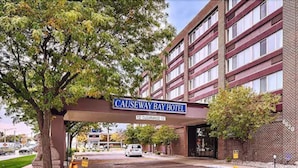 A hotel entrance with a sign reading "CAUSEWAY BAY HOTEL" and a clear road in front. - Causeway Bay Hotel (Lansing)