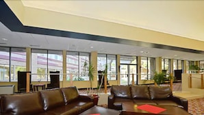 A spacious lobby with leather sofas, large windows, and a modern ceiling design. - Causeway Bay Hotel (Lansing)