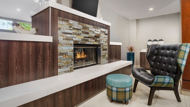 A modern living room with a fireplace, a flat-screen TV, a comfortable chair, and a bowl on the mantel. - Residence Inn by Marriott Seattle Northeast-Bothell (Bothell)