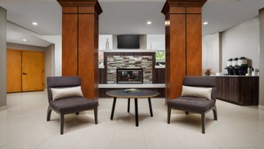 A modern lobby with two armchairs, a round table, a fireplace, and a coffee station. - Residence Inn by Marriott Seattle Northeast-Bothell (Bothell)
