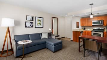 Una sala de estar moderna con un sofá modular, una mesita redonda y una zona de comedor con una mesa de madera y sillas.