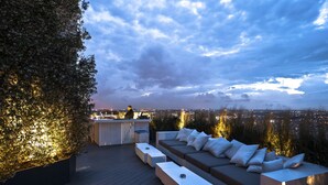 Terraza al aire libre con bar, zona de estar y vista panorámica de la ciudad.