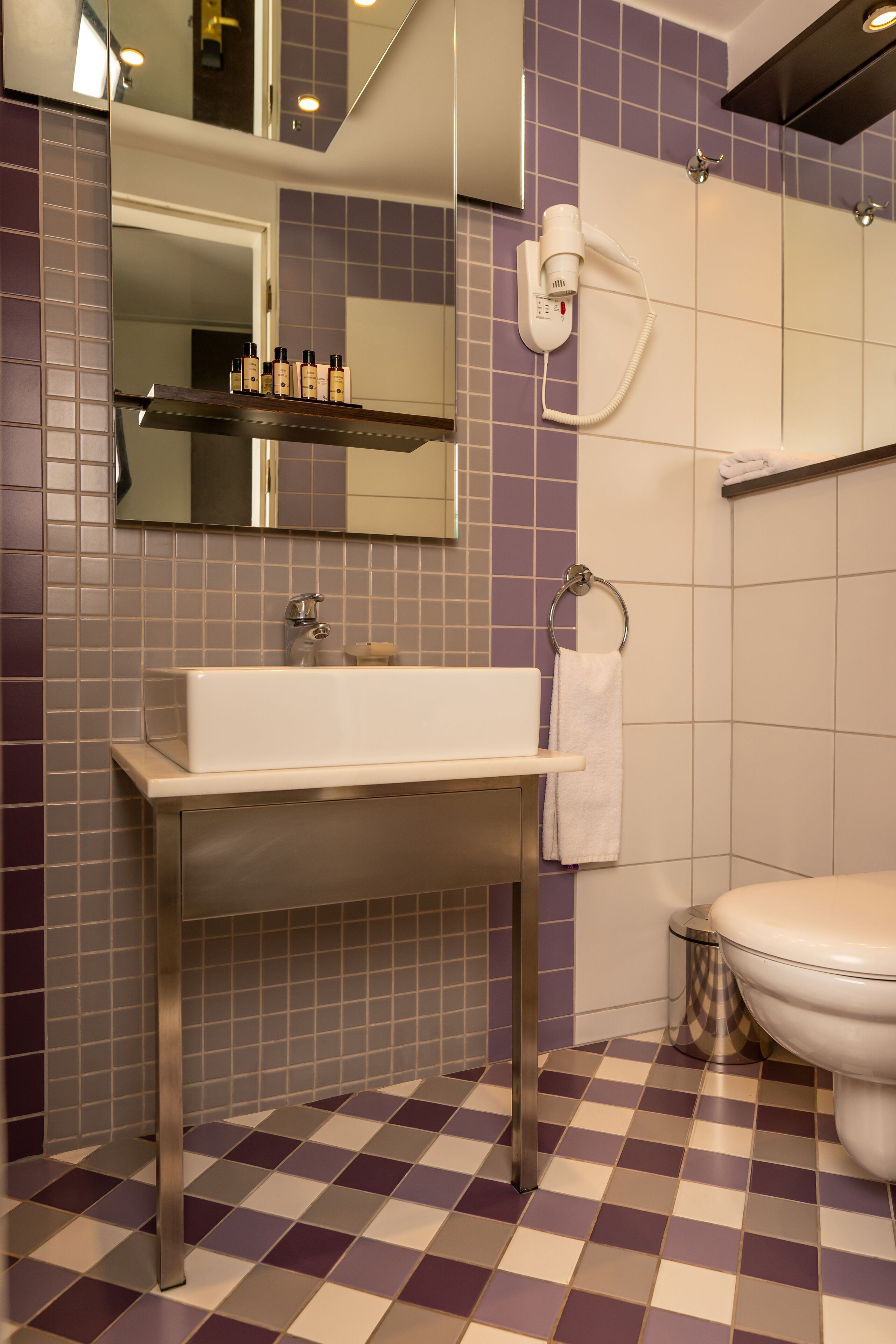A bathroom with a checkered floor, a white sink, a mirror, and a toilet.