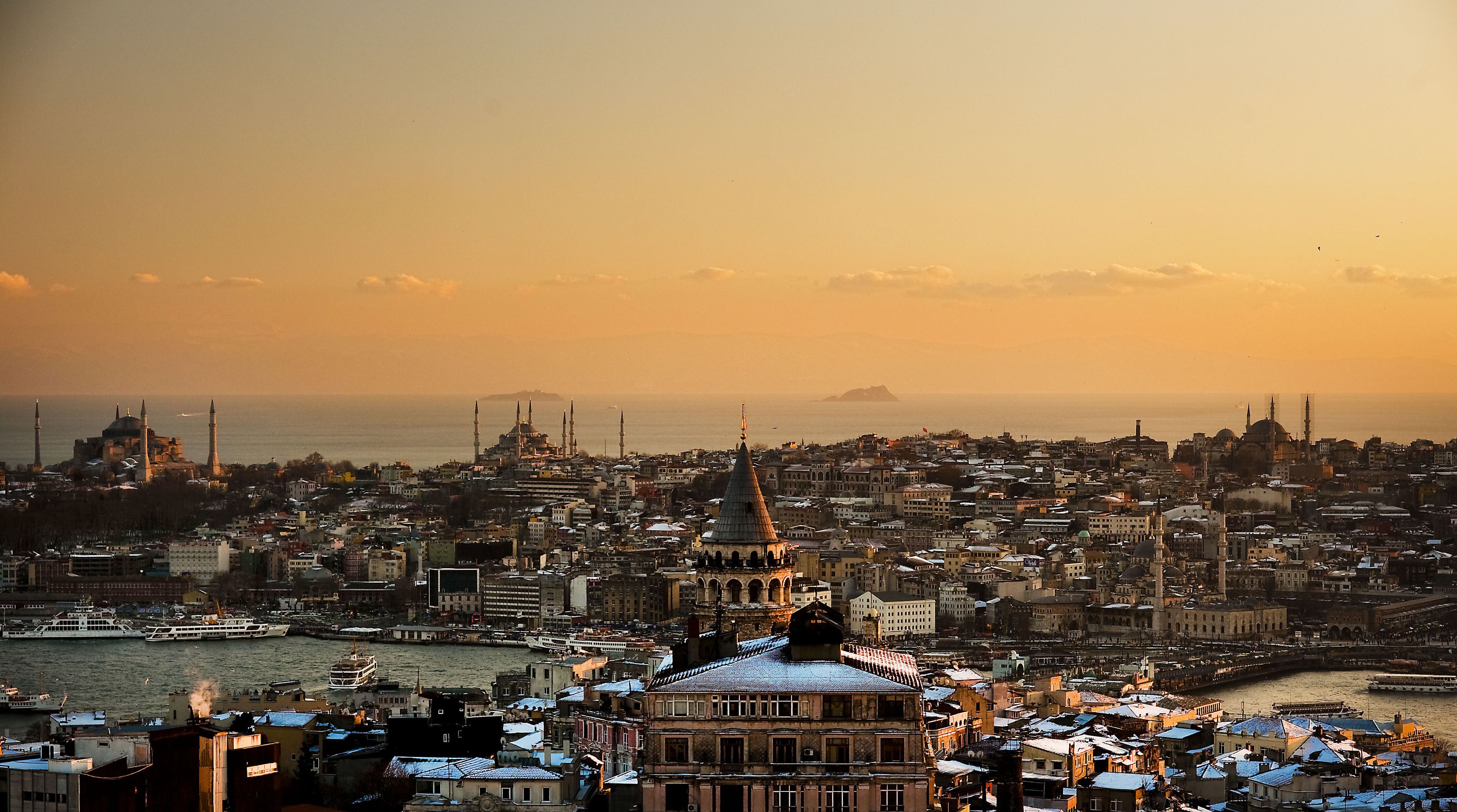 A cityscape with historic architecture, including domes and minarets, and a waterfront with boats.