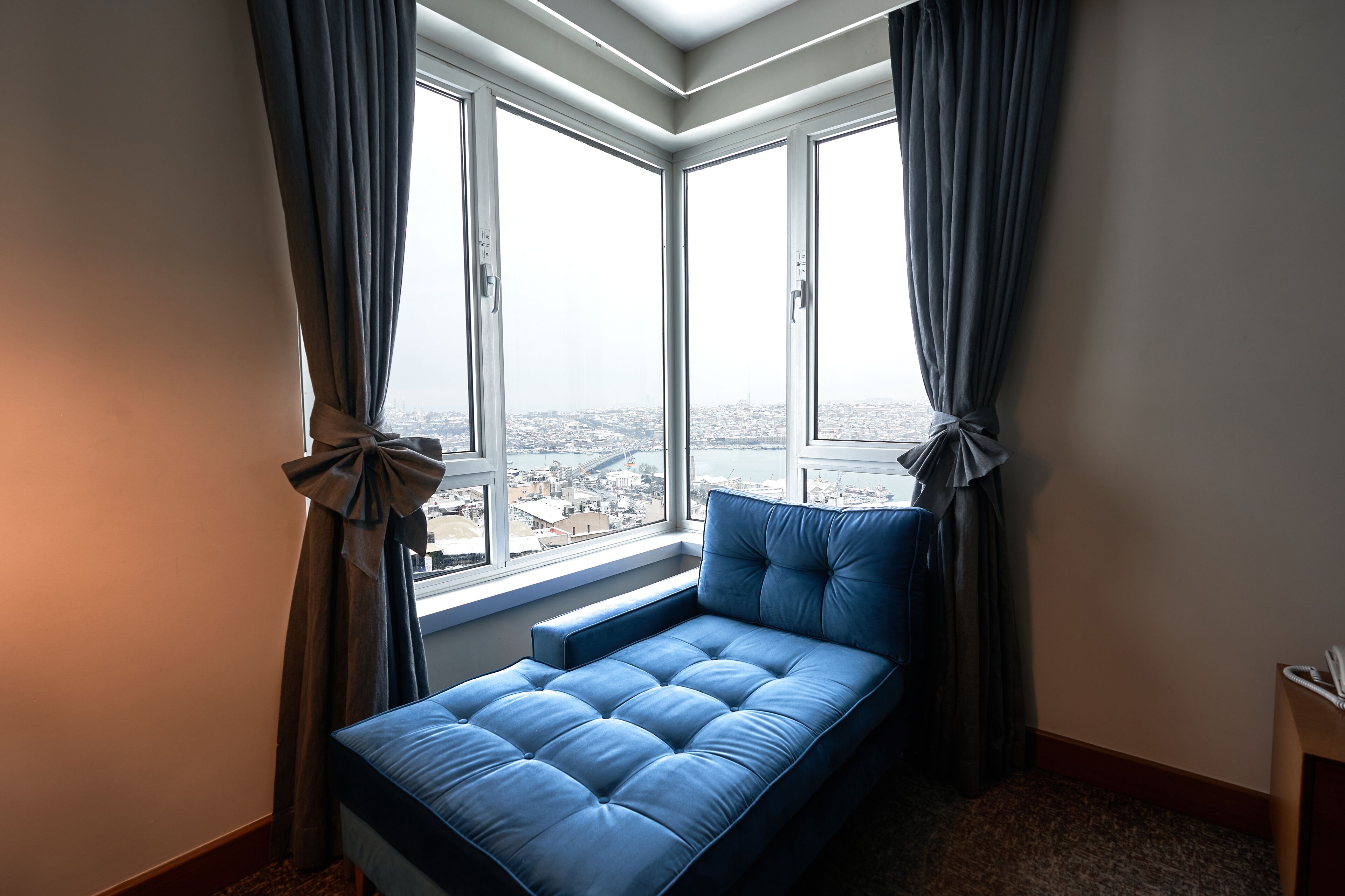 Une chambre avec une grande fenêtre, un lit et des rideaux attachés.
