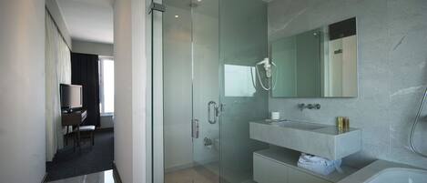 Une salle de bain moderne avec une douche à parois de verre, un grand miroir et une baignoire.