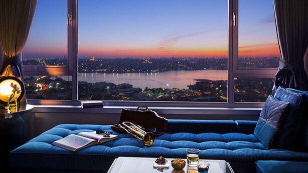 Una habitación con un ventanal grande que da a una vista panorámica de la ciudad al atardecer.