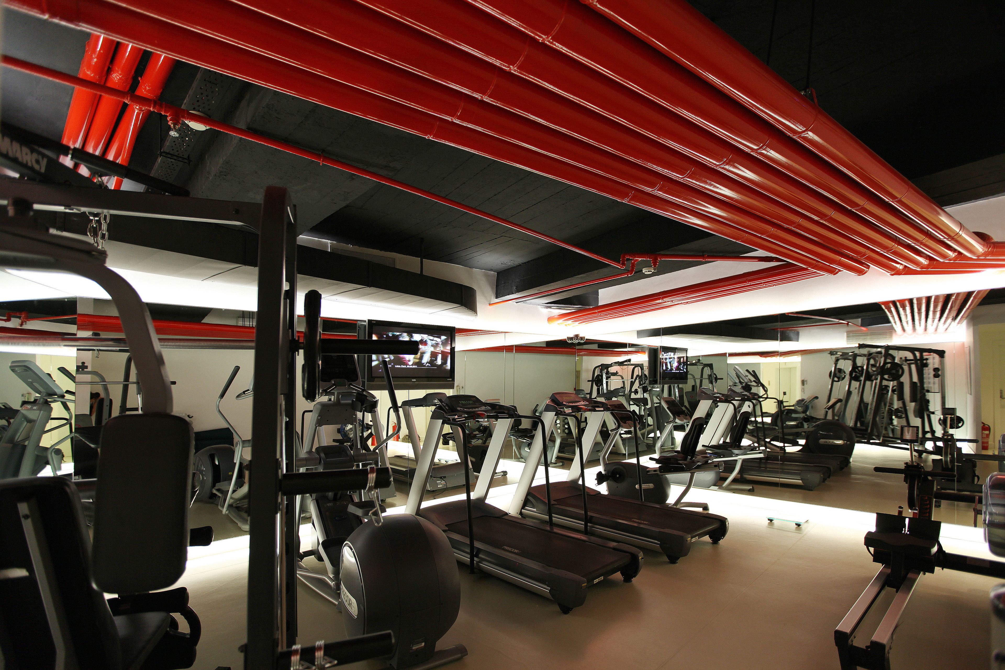 Un gimnasio con cintas de correr, elípticas y equipo de pesas.