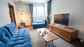 Ein modernes Wohnzimmer mit einem blauen Sofa, einem Holztisch und einem Flachbildfernseher auf einer Holzkommode.