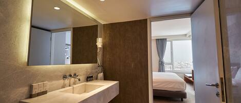 A modern bathroom with a large mirror, dual sinks, and a shower area.