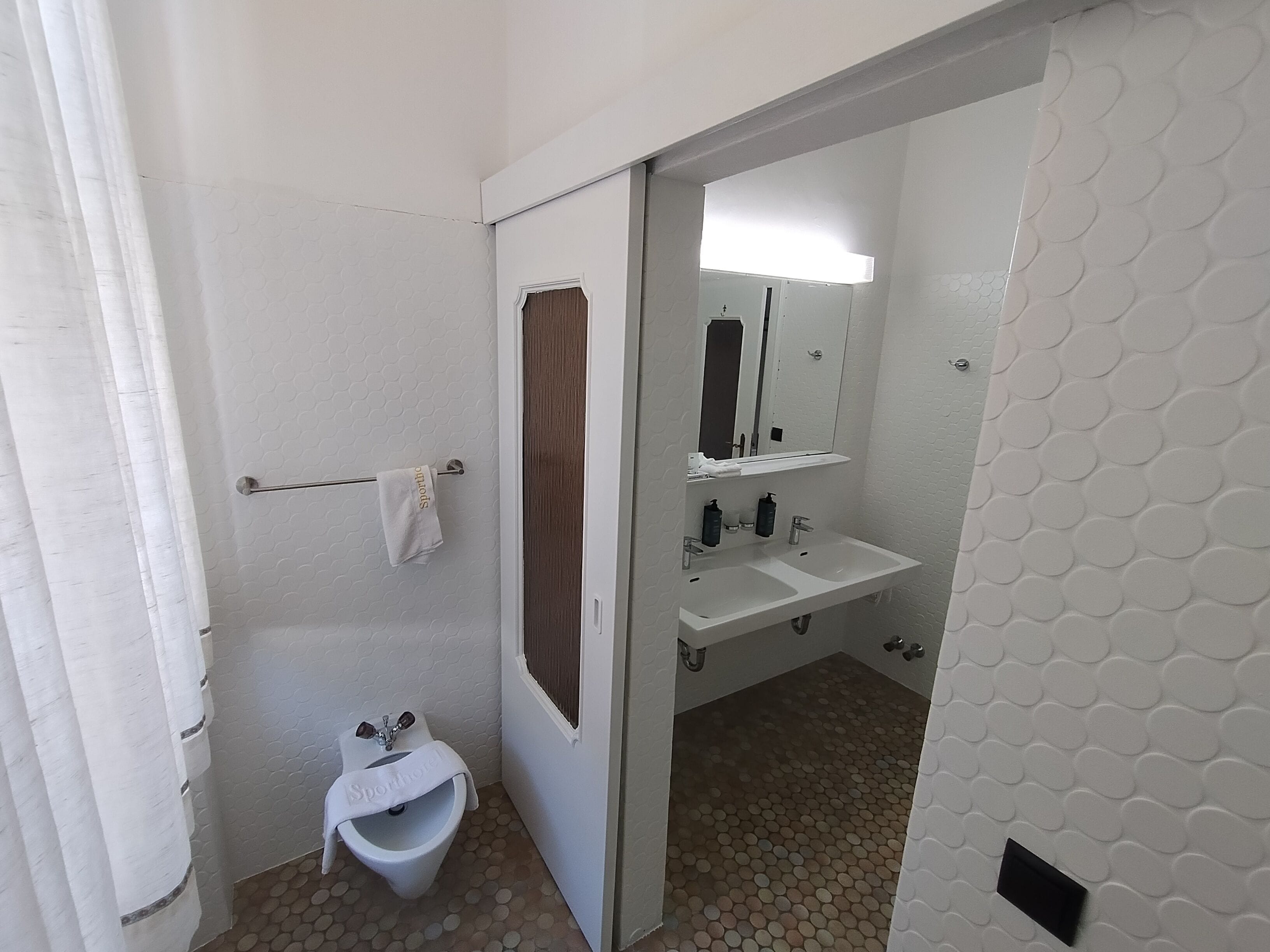 A small, private bathroom with a toilet, bidet, and sink.