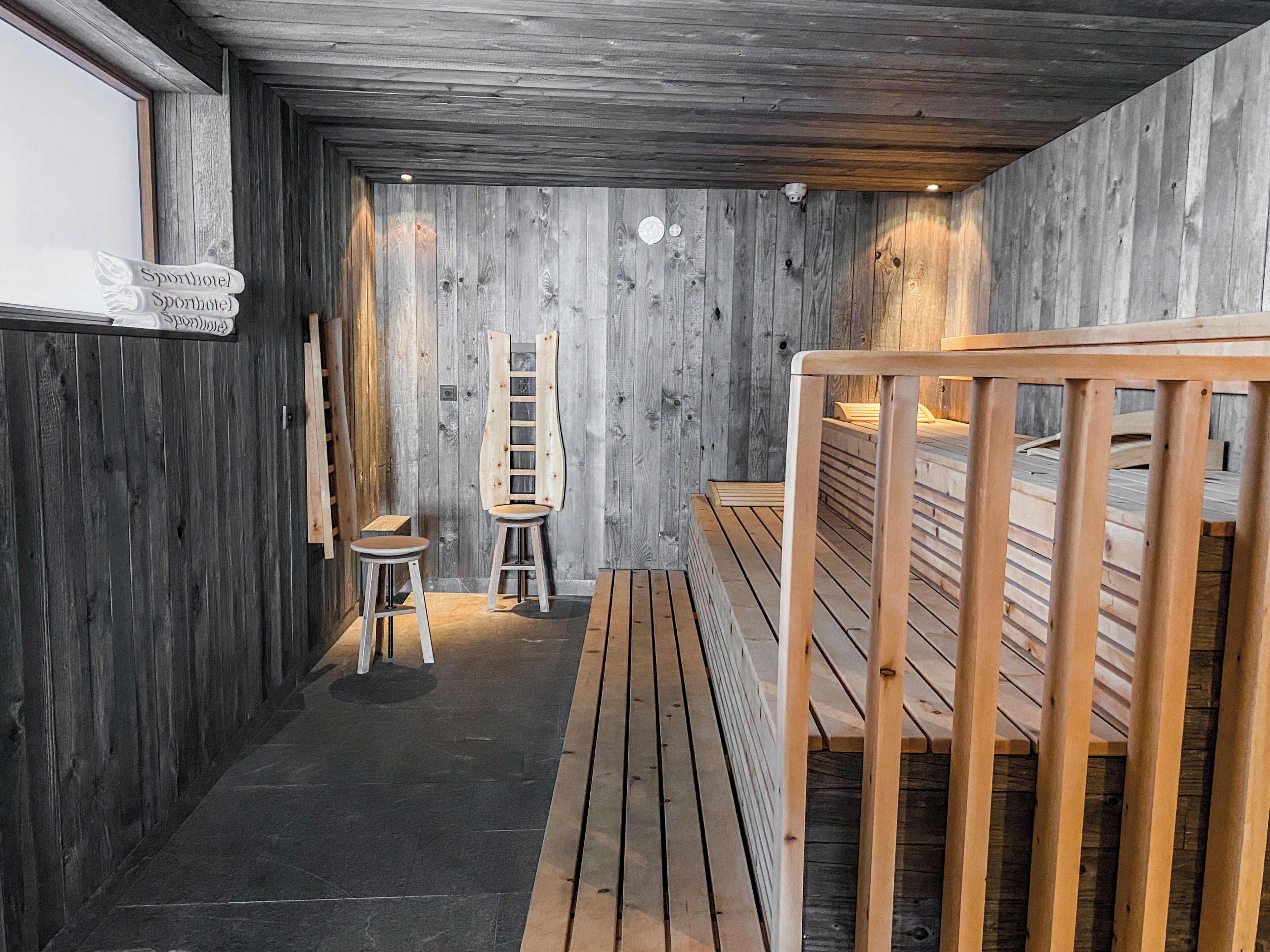 Interior de madera con una litera, dos taburetes y una escalera apoyada en la pared.