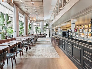 A spacious restaurant with high ceilings, large windows, and a variety of seating options including tables and bar stools. - NH Collection Madrid Suecia (Madrid)