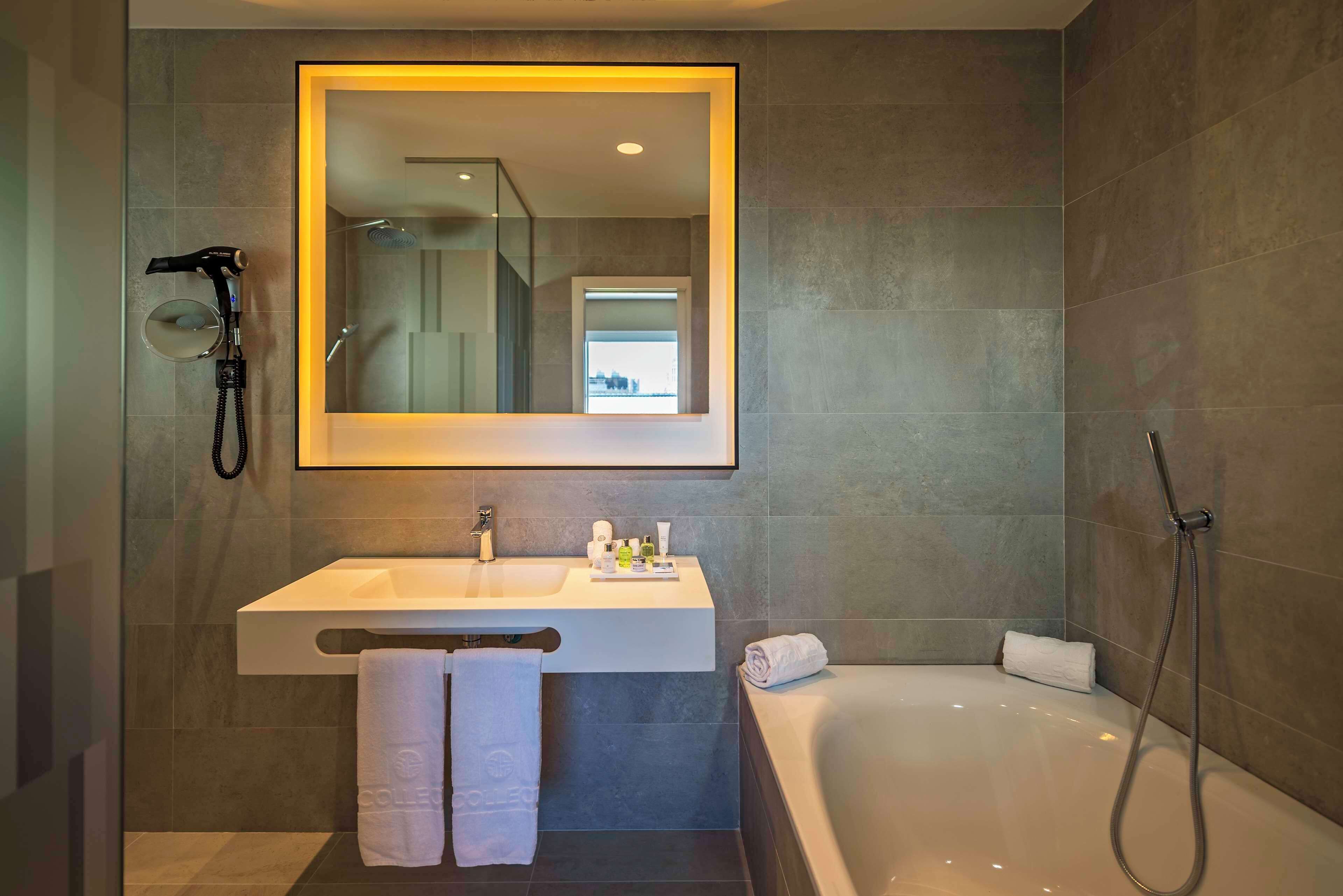 Un baño moderno con un espejo grande, un lavamanos, una ducha y una bañera.