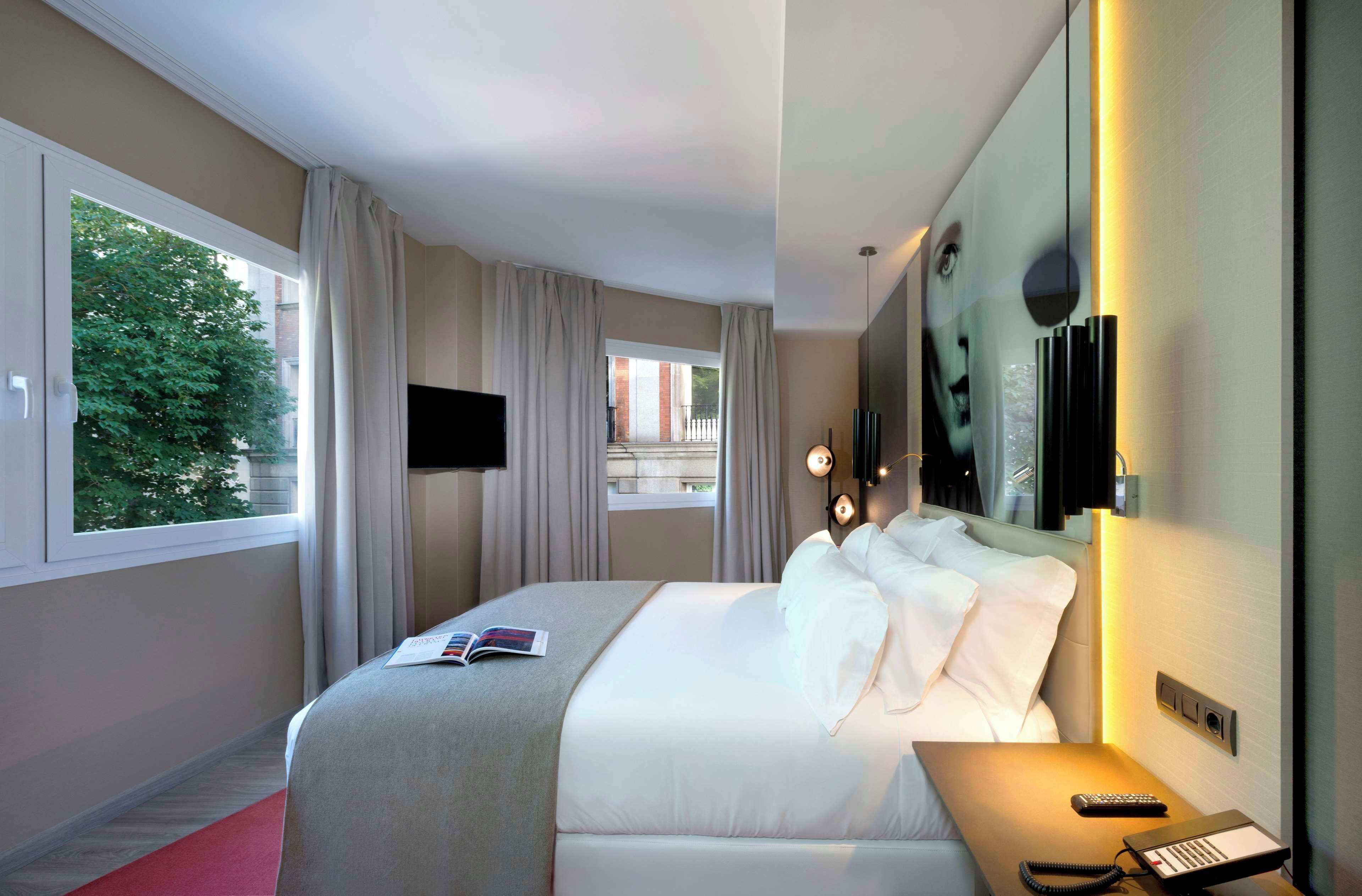 Hotelkamer met een groot bed, een televisie, een nachtkastje met lamp en uitzicht op buiten.