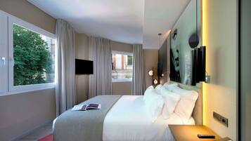 Hotelkamer met een groot bed, een televisie, een nachtkastje met lamp en uitzicht op buiten.