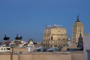 A multi-story building with a prominent statue on the roof, surrounded by other buildings. - NH Collection Madrid Suecia (Madrid)