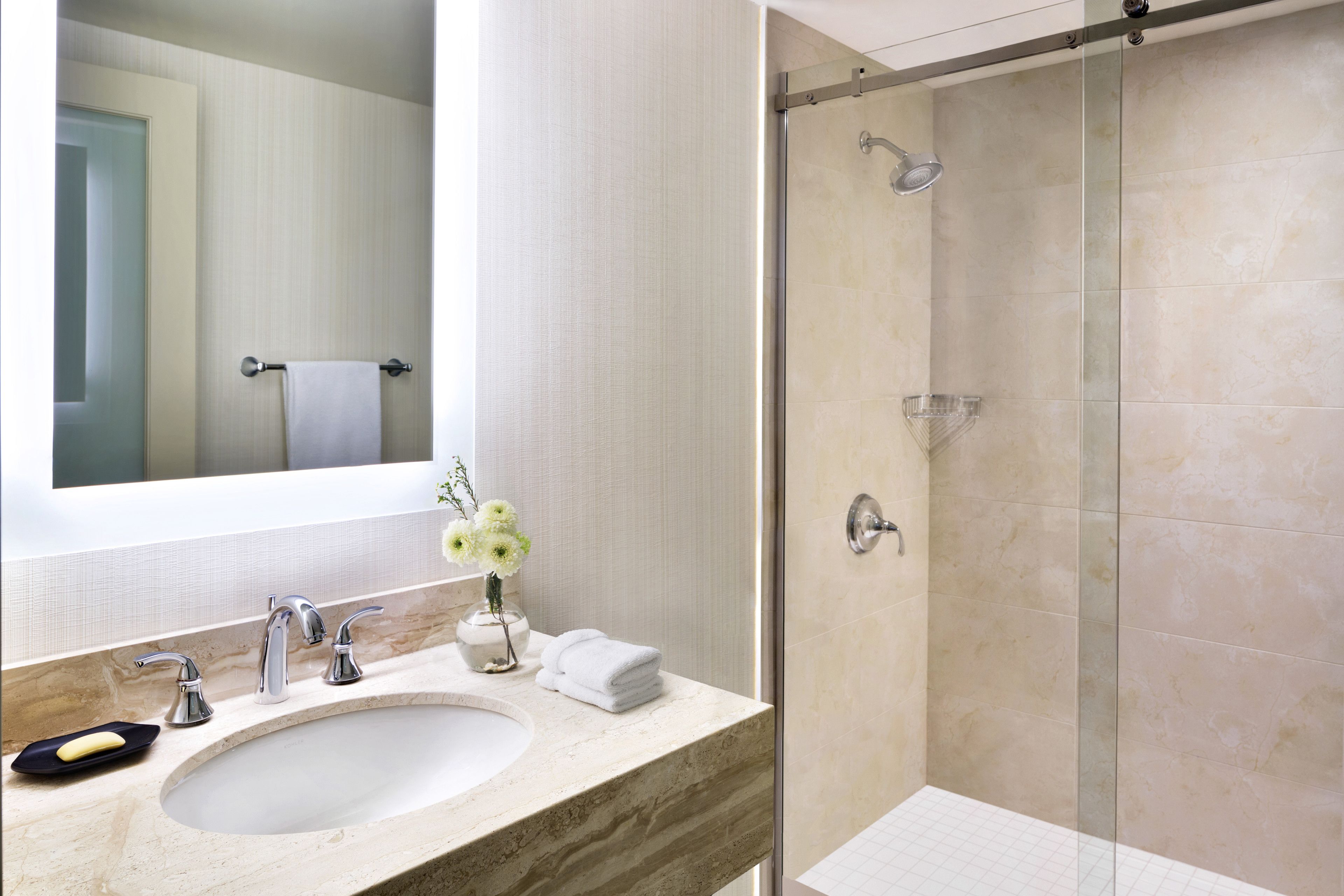 A bathroom with a marble sink, a glass shower enclosure, and a towel rack.