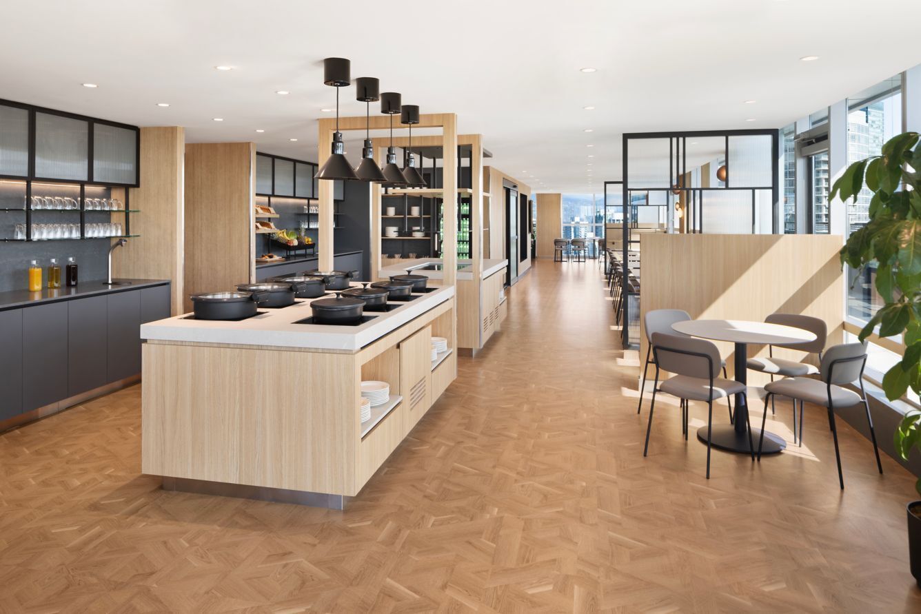 A modern kitchen with a central island, wooden cabinets, and pendant lighting.