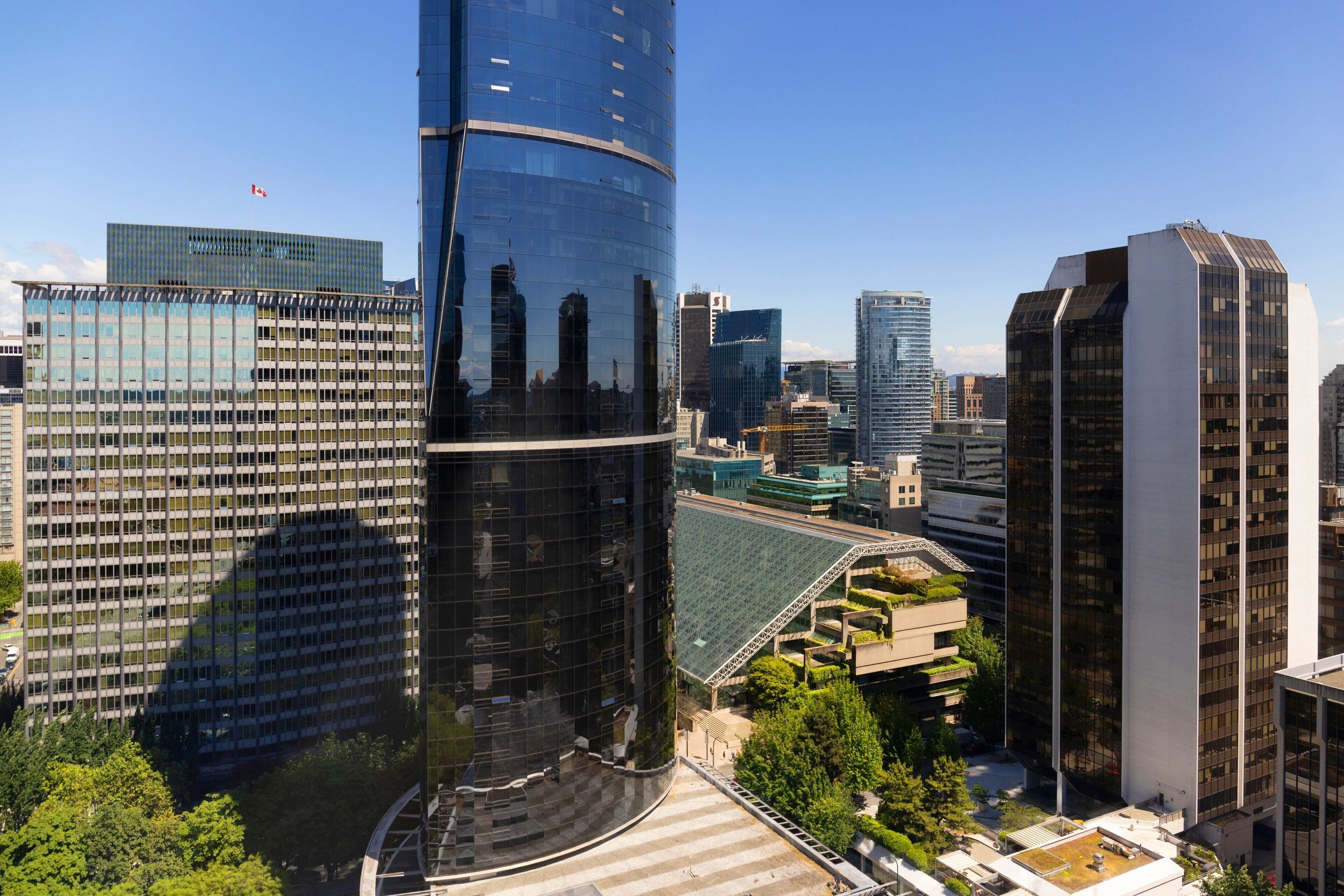 A modern cityscape with high-rise buildings, including a distinctive curved skyscraper and a rectangular building with a flat roof.
