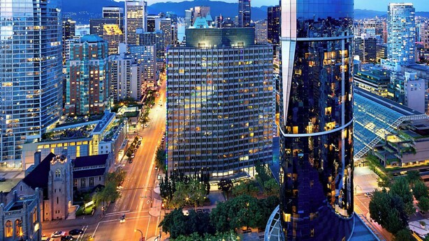 Un paisaje urbano moderno con un rascacielos curvo destacado, rodeado de otros edificios altos.