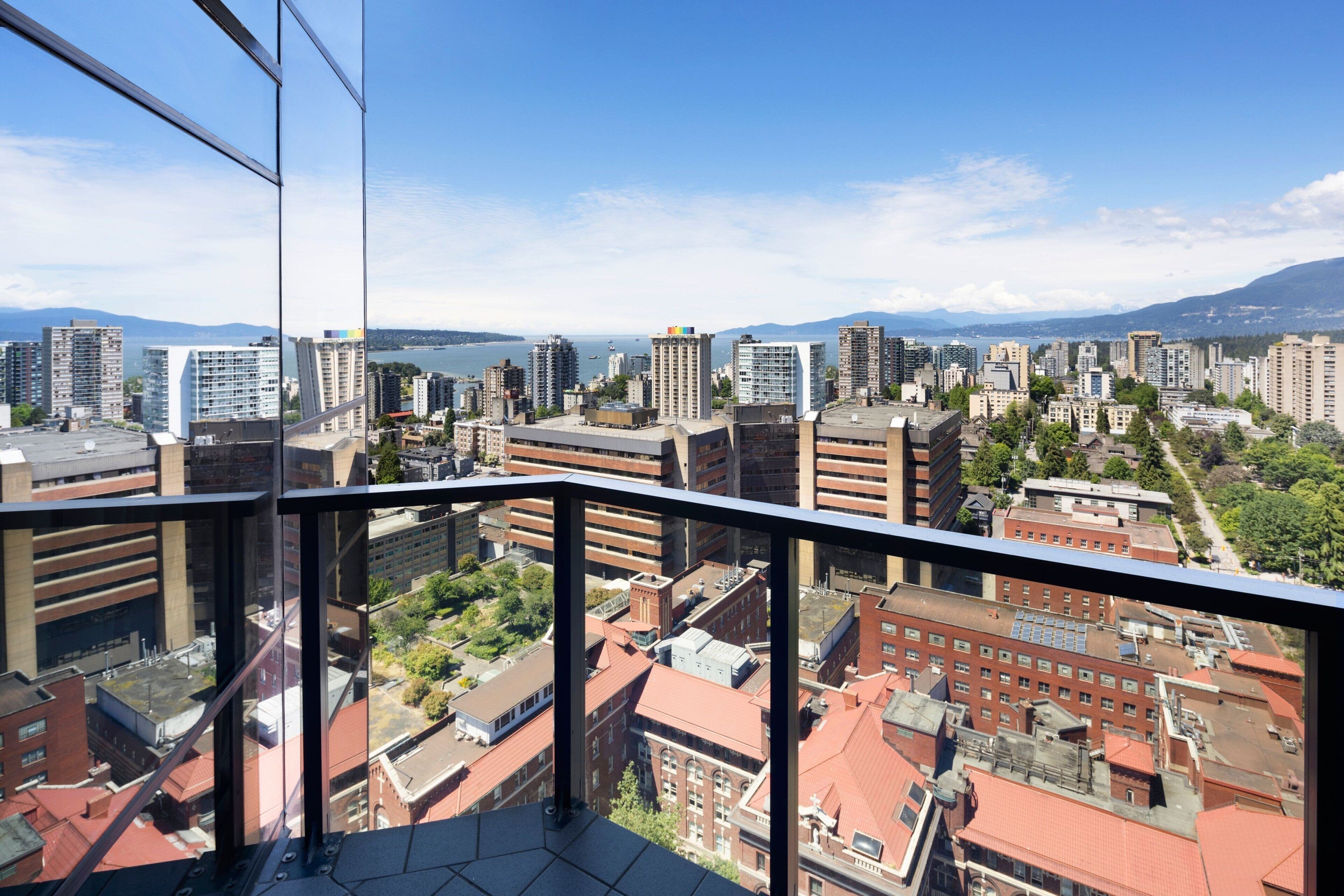 A high-rise building with a view of a cityscape, including various buildings and a body of water in the distance.