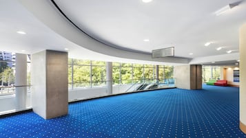 Relax in a spacious indoor area with high ceilings and large windows offering a view of the surrounding amenities.