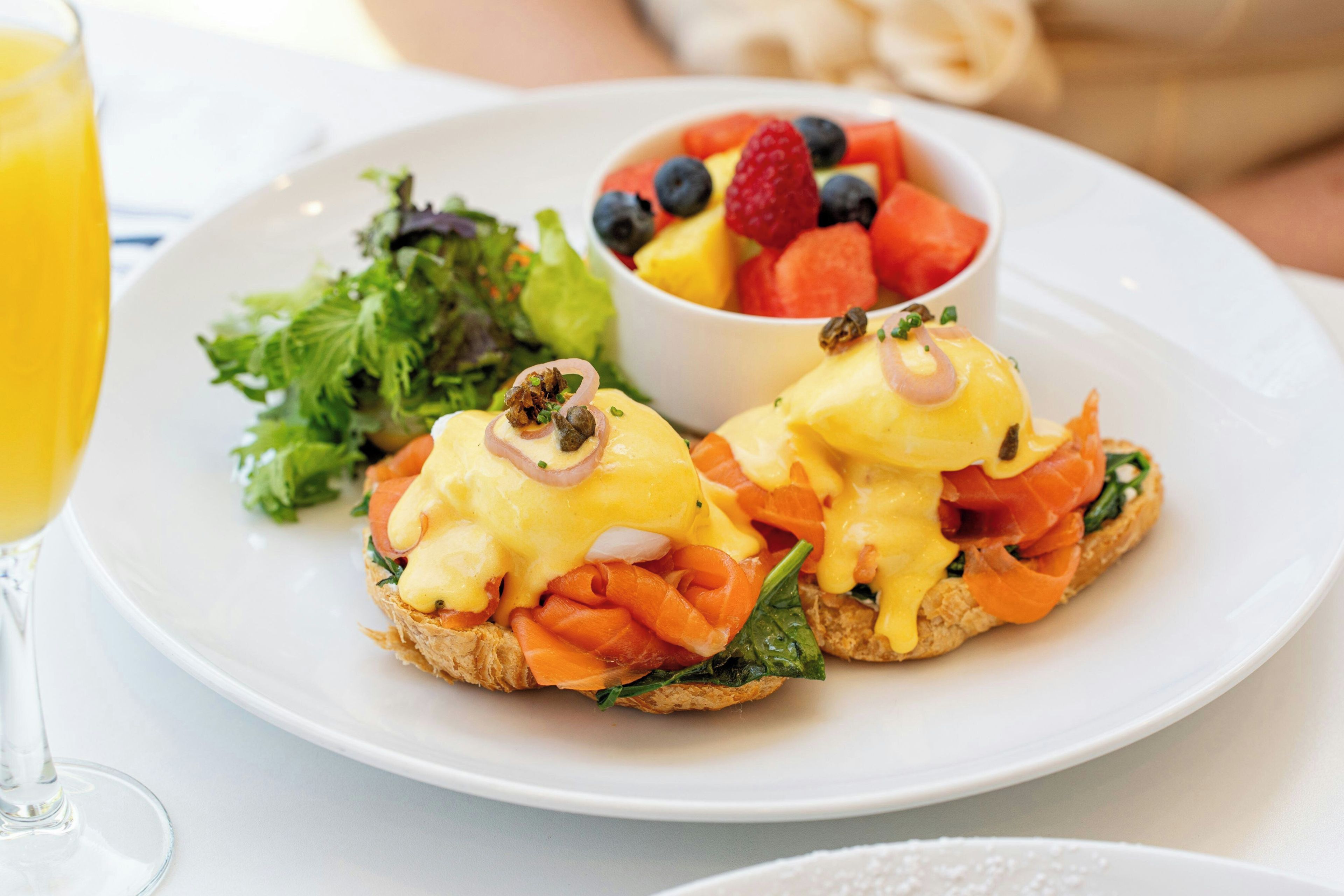 Un plato con huevos benedictinos y una ensalada acompañante.