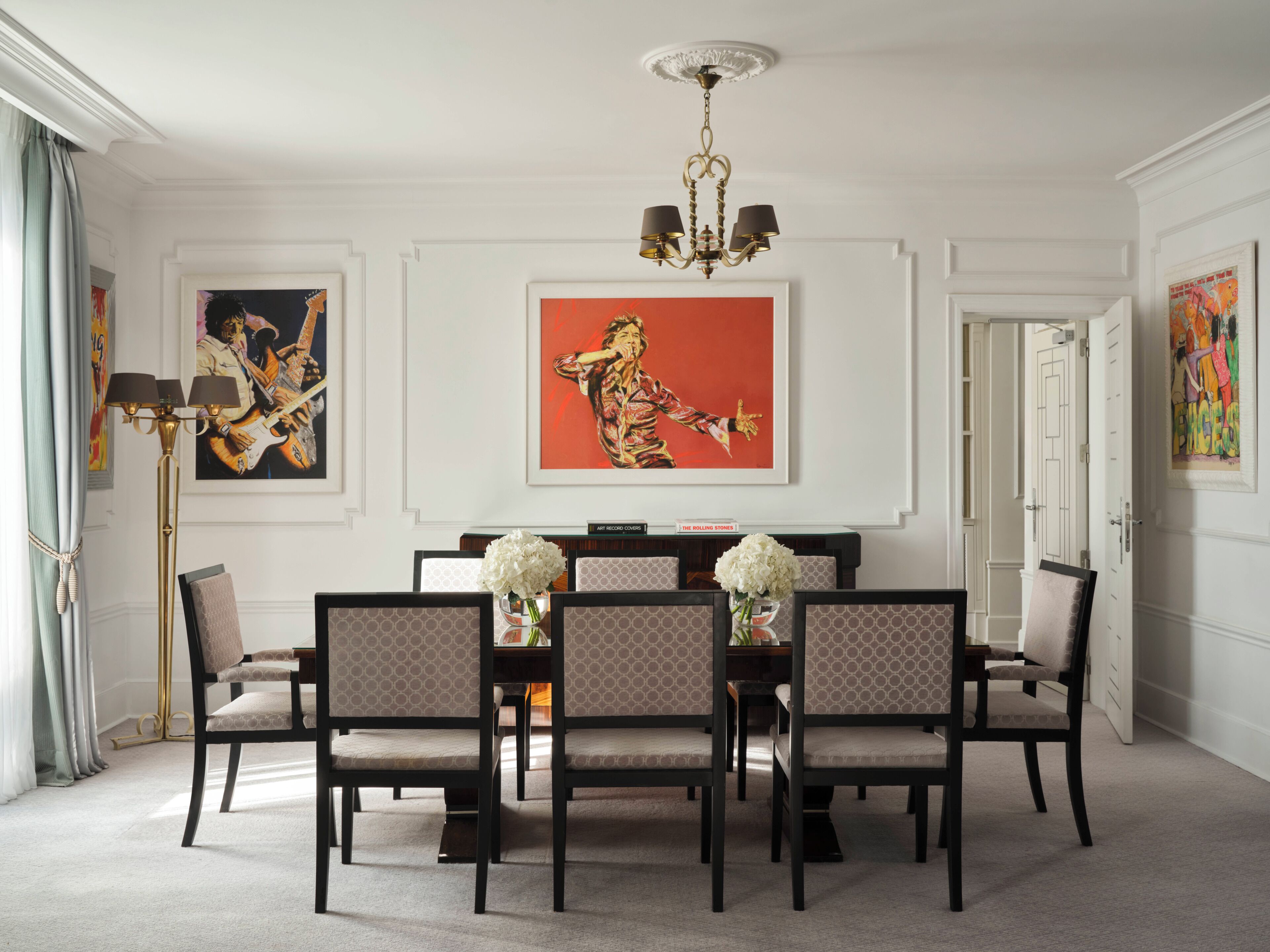 Un comedor con candelabro, obras de arte enmarcadas y una mesa dispuesta para seis comensales.