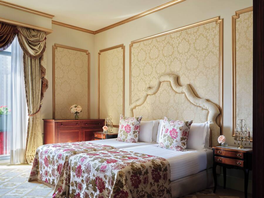 Ein Schlafzimmer mit einem großen Bett, einem Nachttisch, einer Kommode und einem Fenster mit Vorhängen.