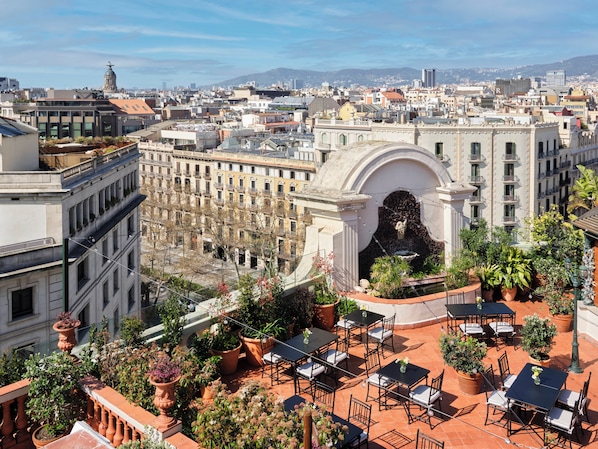 A rooftop patio with outdoor seating and a fountain, surrounded by terracotta pots and potted plants. - Hotel El Palace Barcelona (Barcelona)