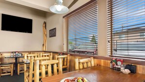Un interior de restaurante con muebles de madera, un televisor de pantalla plana y una ventana con persianas.