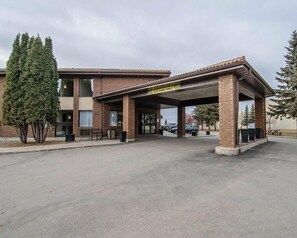 Un edificio con entrada cubierta y un letrero que dice '8FT CARS ONLY', junto a un área de estacionamiento.