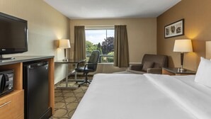 Ein Hotelzimmer mit Bett, Schreibtisch, Stuhl, Fernseher und Kühlschrank.