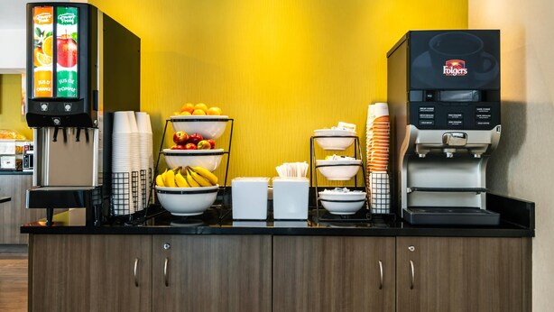 Ein Frühstücksbuffet mit Saftspender, Obstschalen und einer Kaffeemaschine.