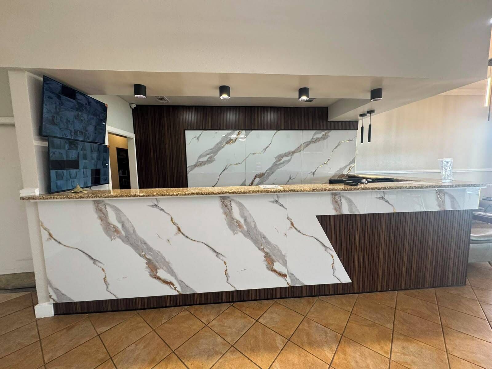 Une cuisine moderne dotée de plans de travail en marbre, de meubles en bois foncé et d’appareils électroménagers intégrés.
