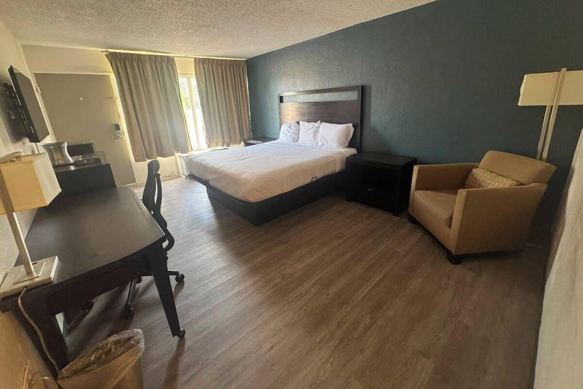 A hotel room with a bed, a desk, a chair, and a TV.