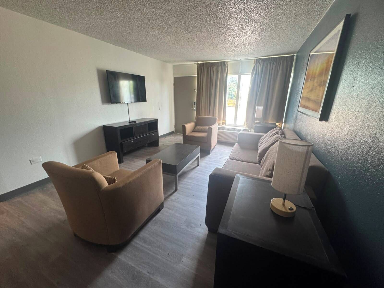A living room with a flat-screen TV, a sofa, a coffee table, and a lamp.