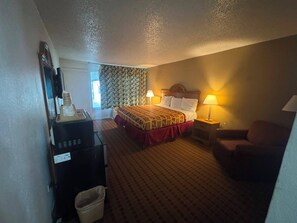 A hotel room with a bed, two bedside lamps, a desk with a computer, and a chair. - Express Inn & Suites Greensville TX (Greenville)