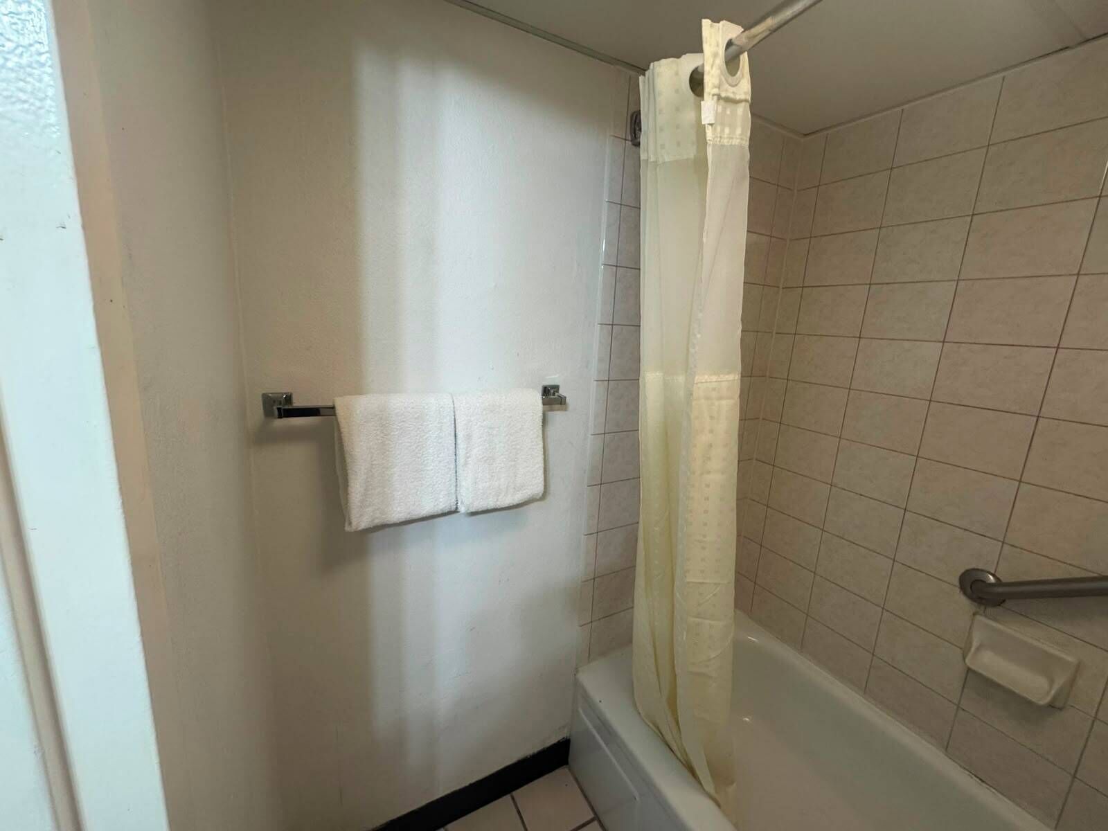 A bathroom with a bathtub, a shower curtain, and two towels hanging on a rack.