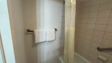 A bathroom with a bathtub, a shower curtain, and two towels hanging on a rack.