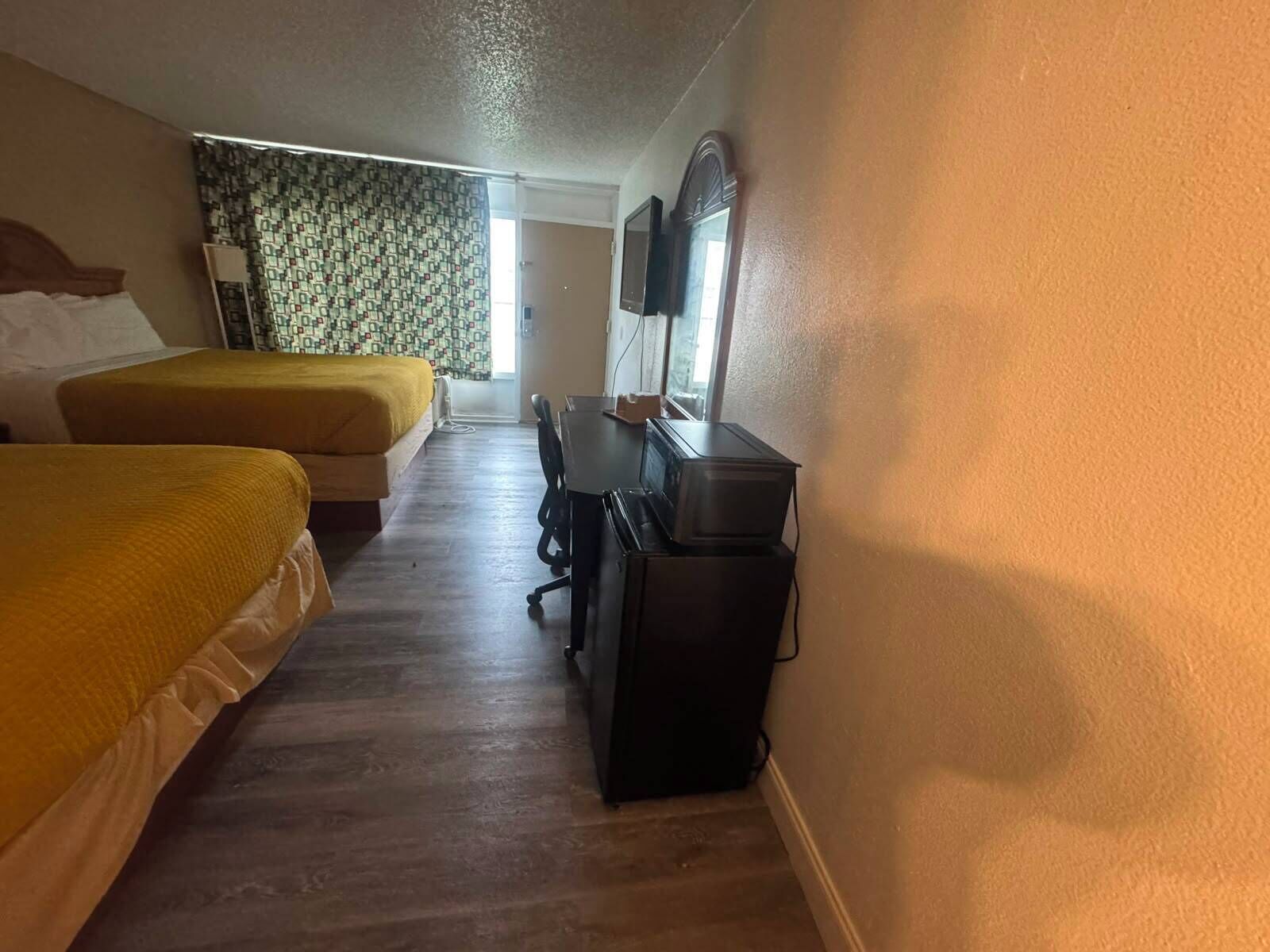 Ett hotellrum med två sängar, ett skrivbord, en stol, en tv och en garderob.