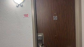 Puerta con un letrero de no fumar, cerradura con teclado numérico e indicación de la habitación 102.