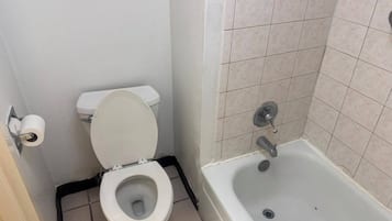 Une salle de bain avec des toilettes, un rouleau de papier toilette et une baignoire.