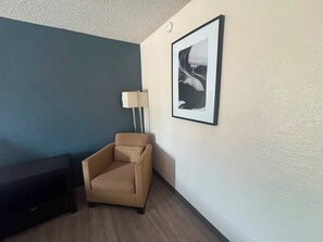 A room with a beige armchair, a framed picture on the wall, and a floor lamp. - Express Inn & Suites Greensville TX (Greenville)