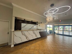 A spacious lobby with a marble reception desk, modern lighting, and large windows. - Express Inn & Suites Greensville TX (Greenville)