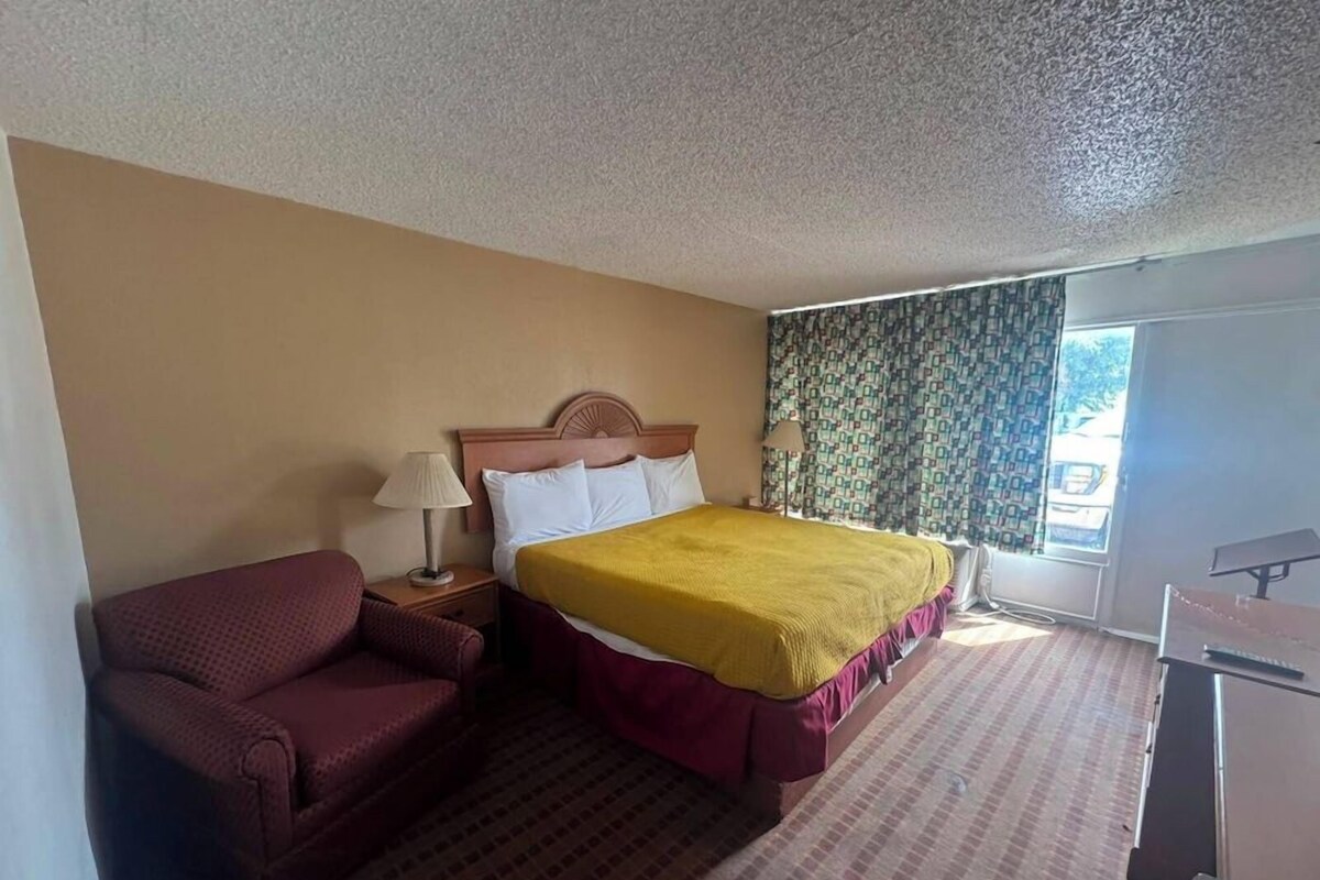 A hotel room with a bed, a sofa, a desk, and a window with curtains.