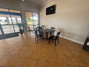A conference room with a large table and chairs, a flat-screen TV on the wall, and a view of the outside through large windows. - Express Inn & Suites Greensville TX (Greenville)